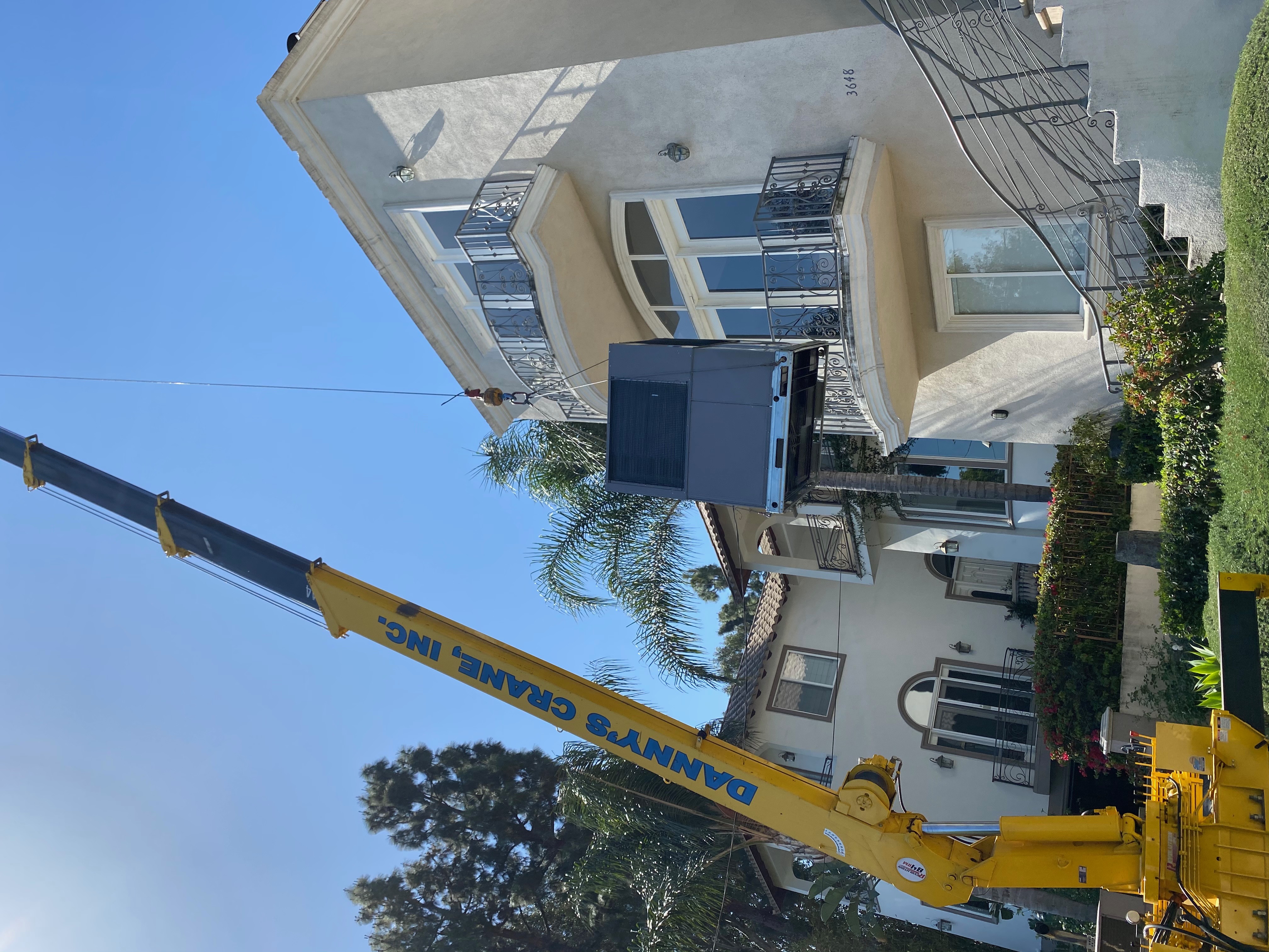 Crane installing a new air conditioning unit on a residential rooftop